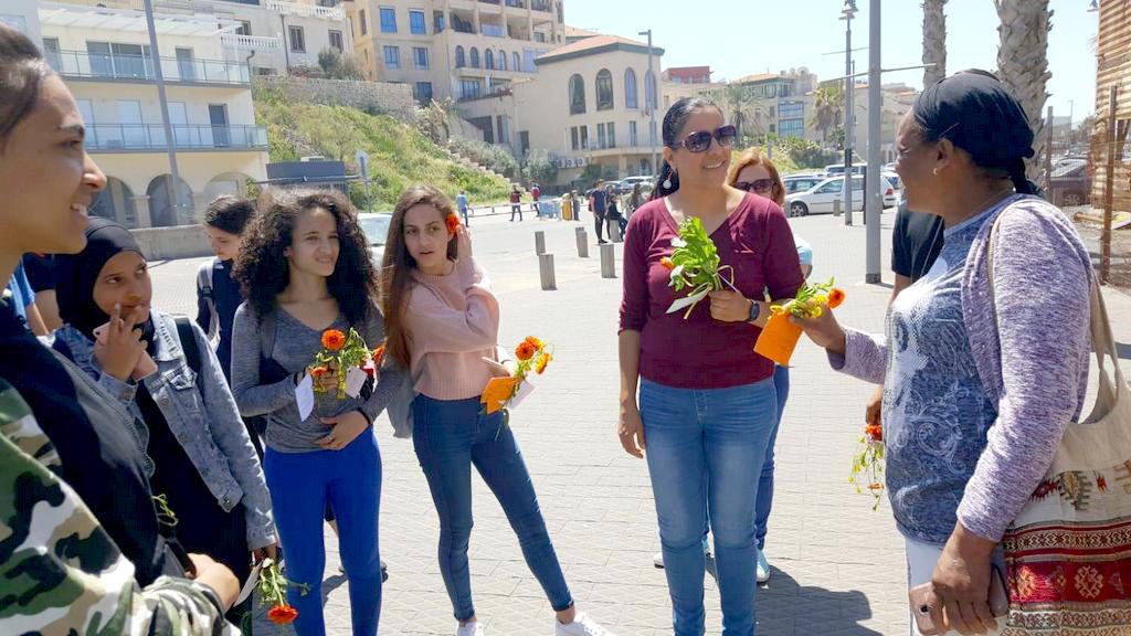 תלמידי עתיד לוד וגולדה פת מחלקים מסר עם פרח בנמל יפו
